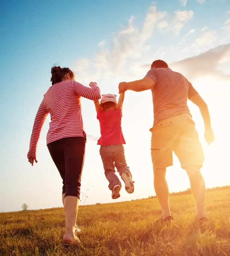 Happy family playing outdoors, parents with child in nature